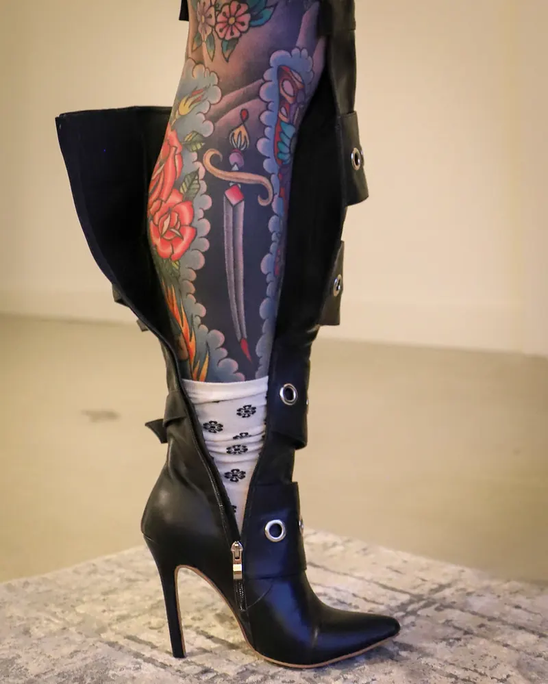 Tattooed leg in a black boot