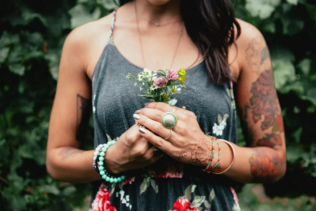 Woman with tattooed arms holding flowers