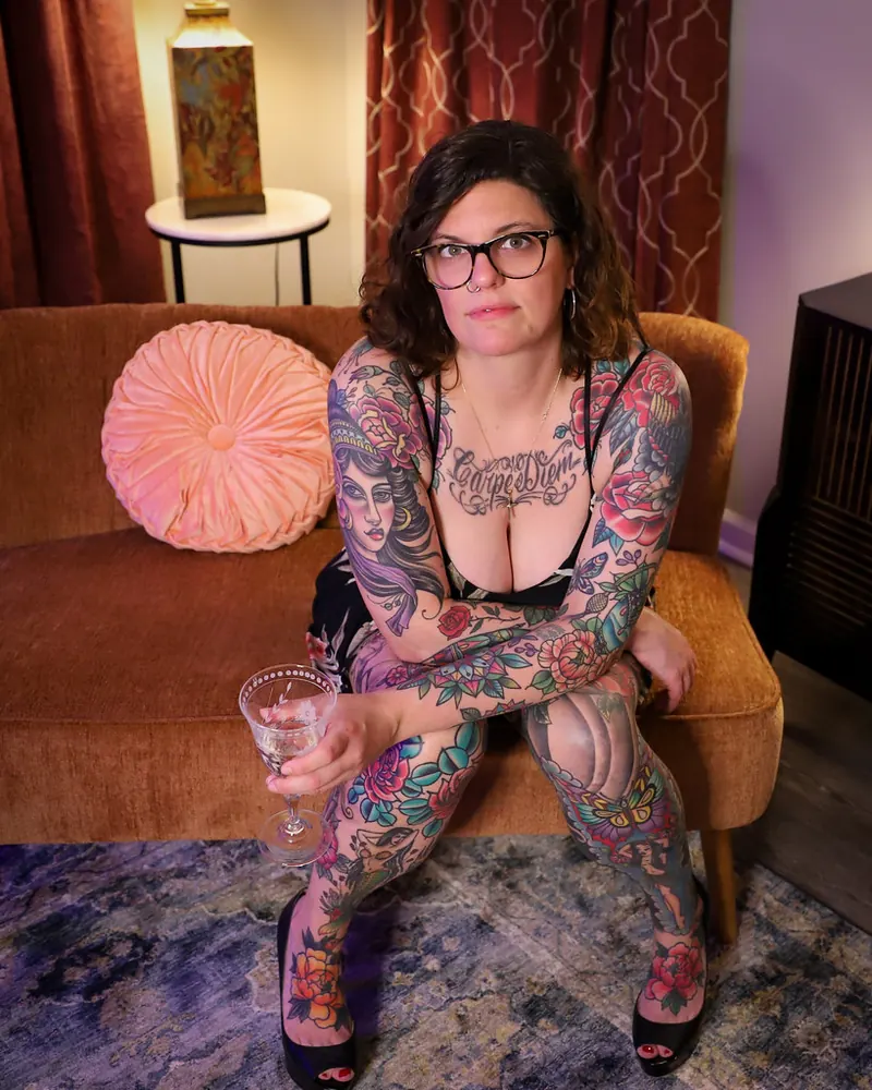 Heavily tattooed woman sitting in an armchair