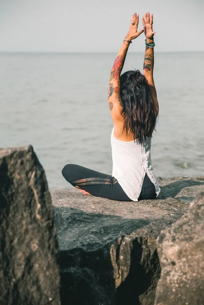 Woman with tattooed arms sitting by the sea