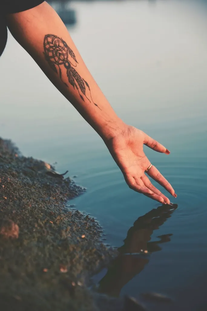 Tattooed arm reaching into the water